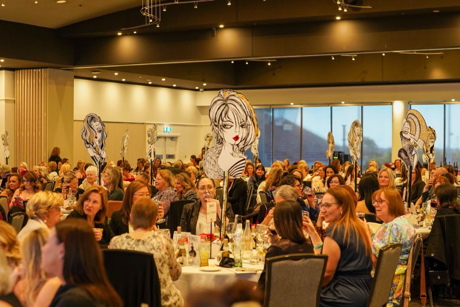 Guests chatting at round tables during a large women's luncheon